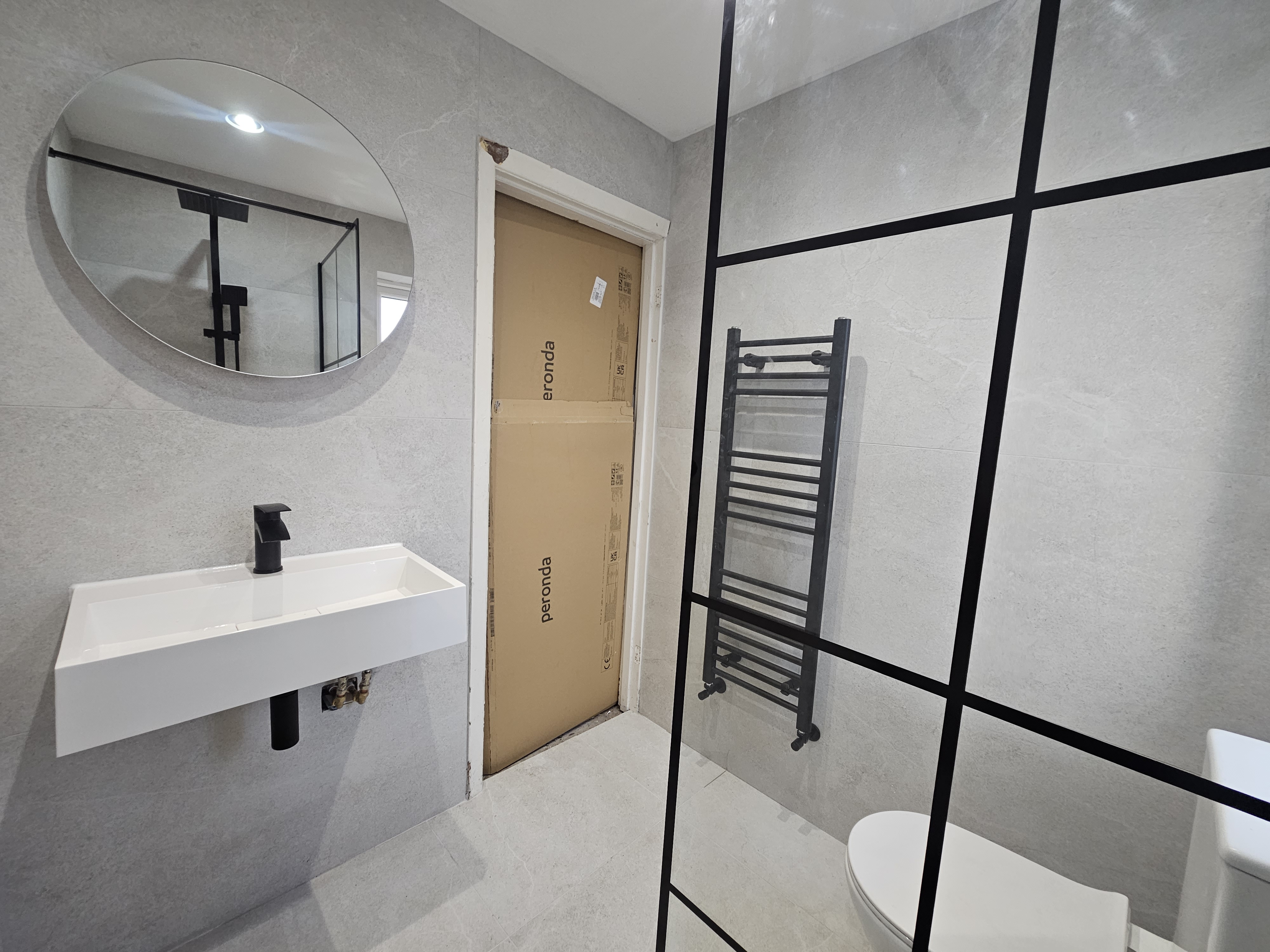 Minimal grey bathroom with floating basin and black framed shower screen