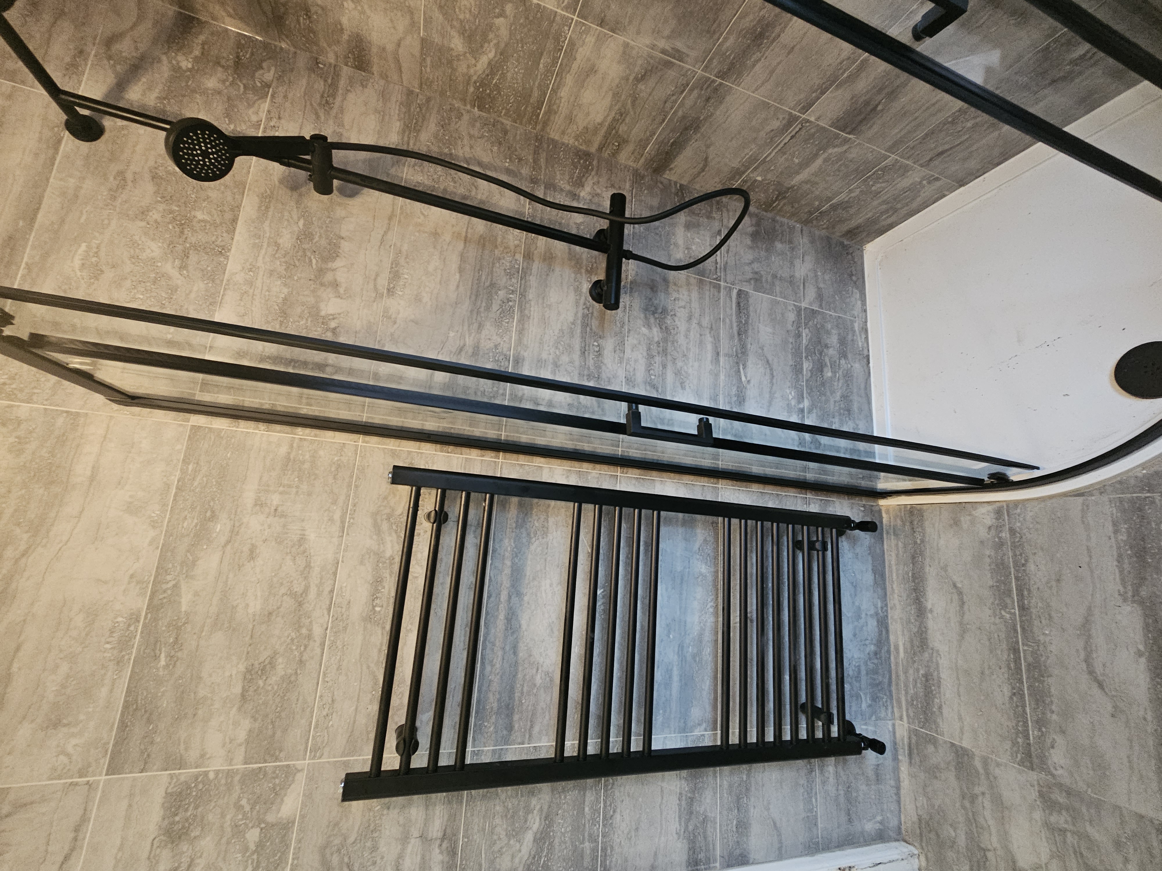 Warm stone-effect bathroom with black fittings and coordinated radiator