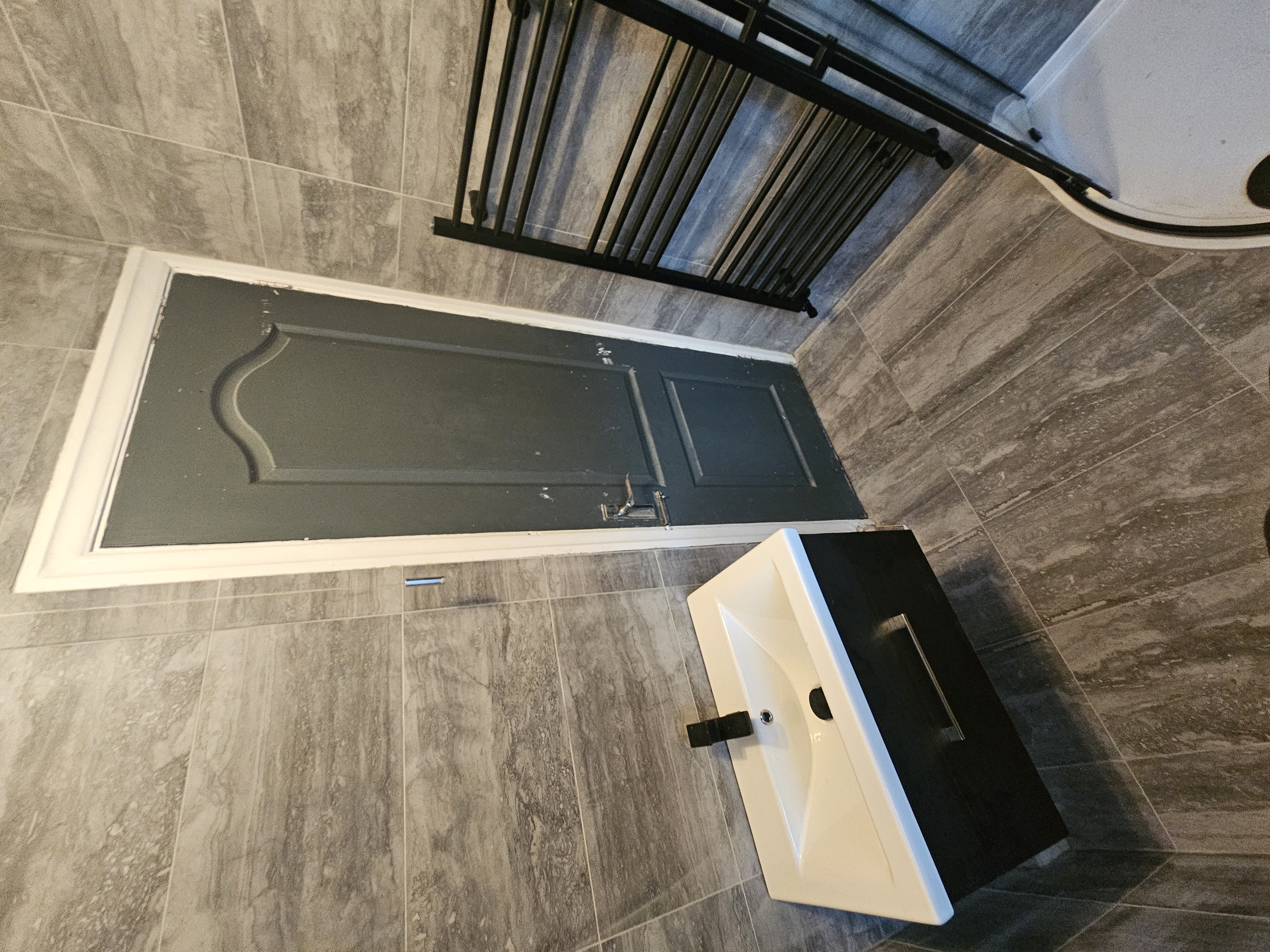 Bathroom with black shower detailing and warm stone-effect tiling