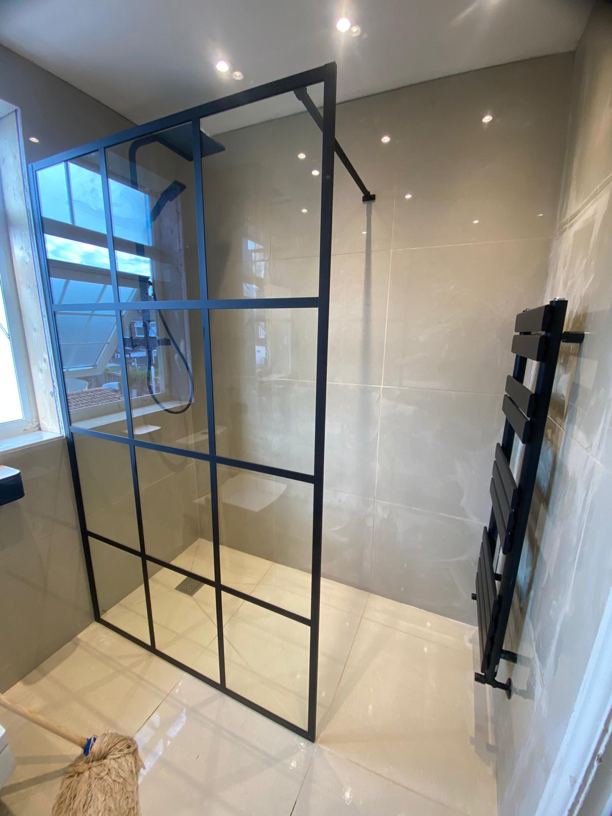 Walk-in shower with black framed glass screen and black fittings