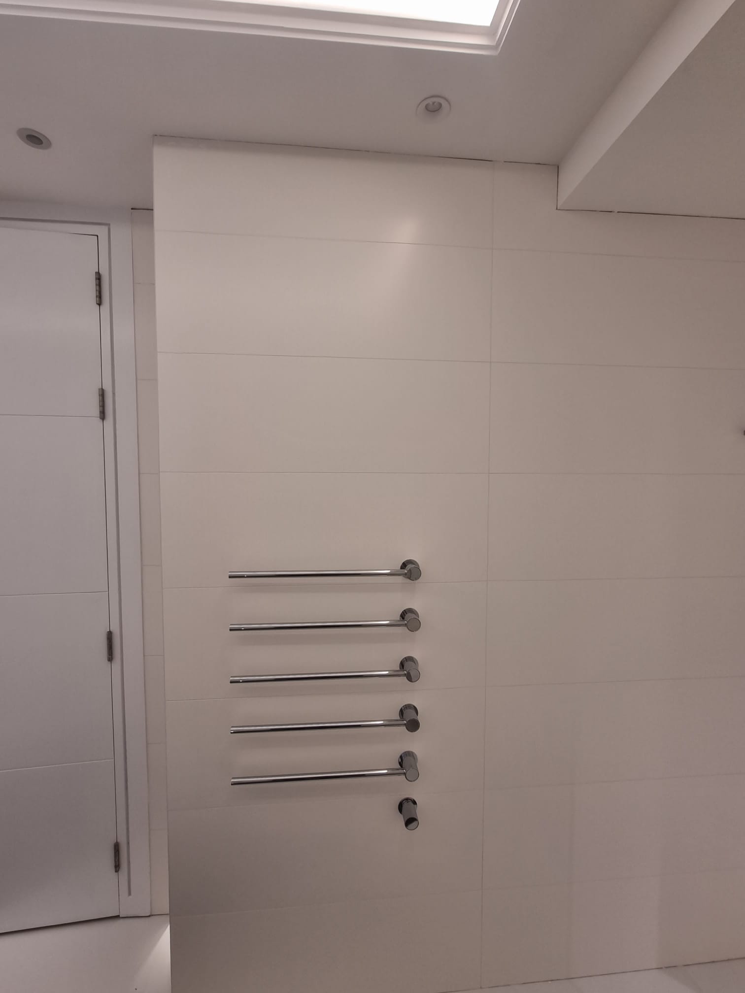 Minimal bathroom with integrated chrome heated towel rail installation