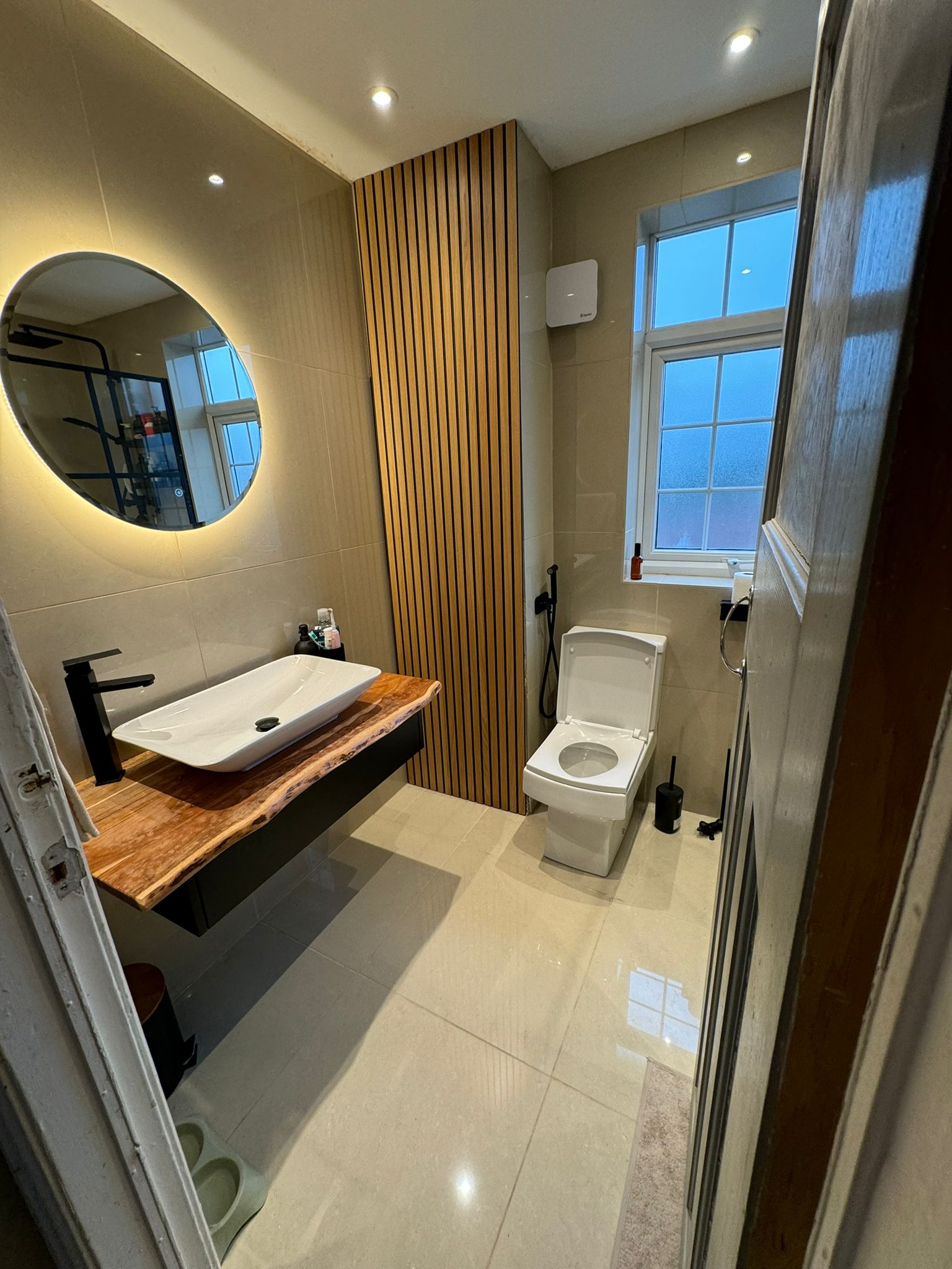 Contemporary bathroom with timber feature wall, illuminated mirror and black brassware