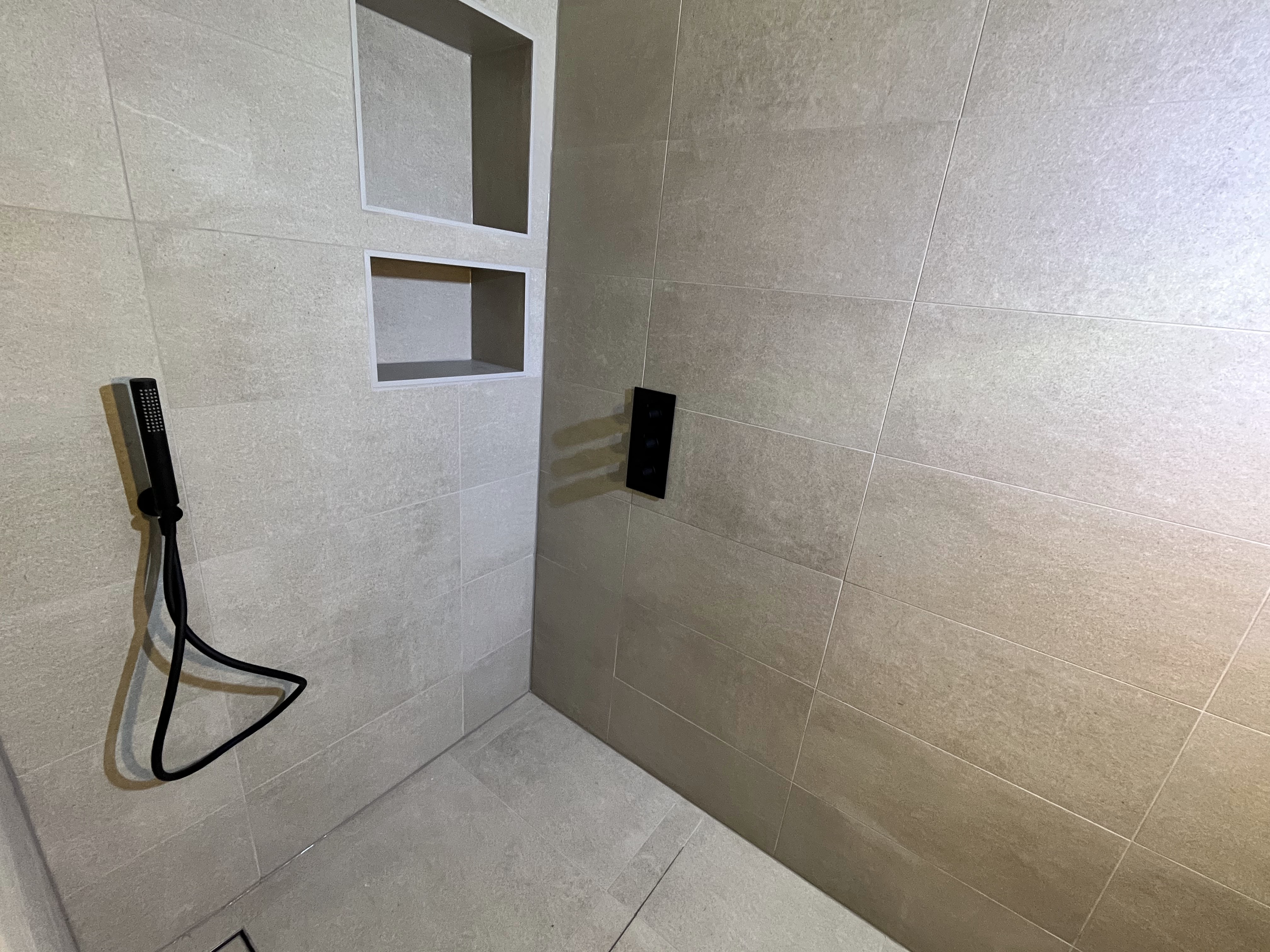 Finished shower installation with recessed storage and black fittings